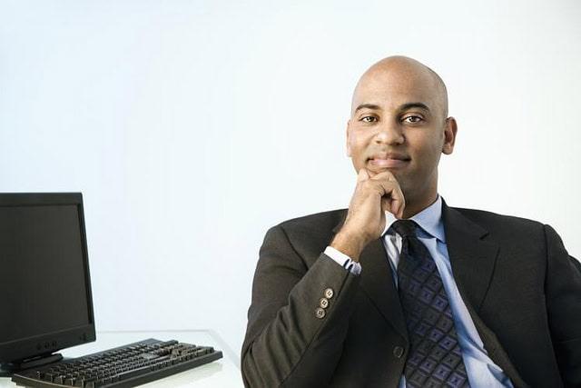 Confident professional man in suit poses with thoughtful expression, symbolizing self-belief and motivation.